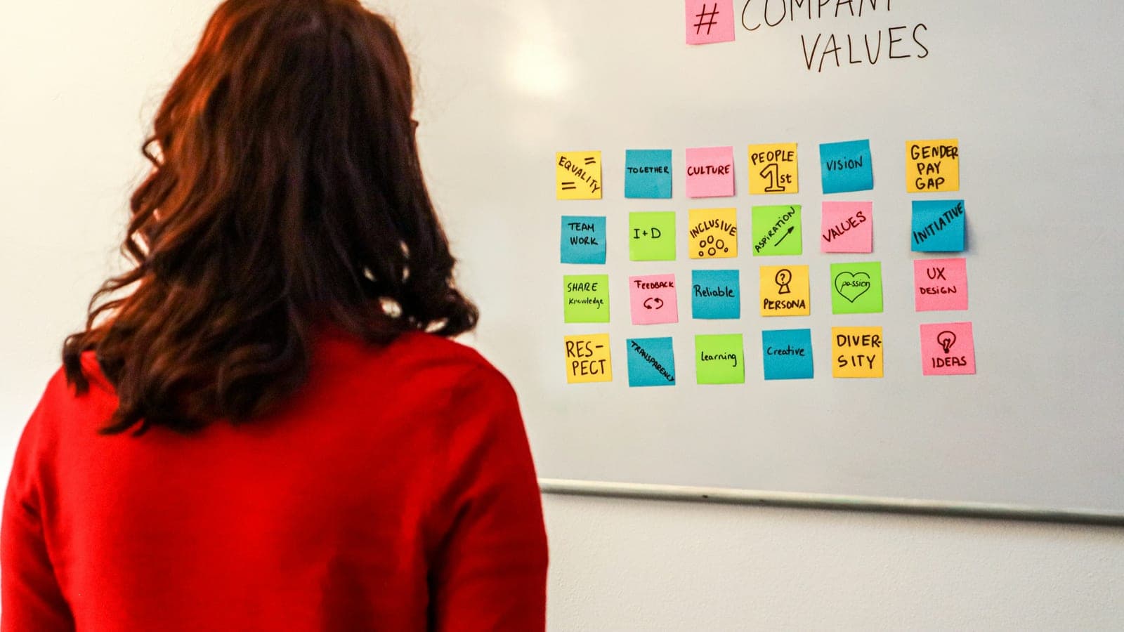 A woman standing in front of a white board with company values written on it