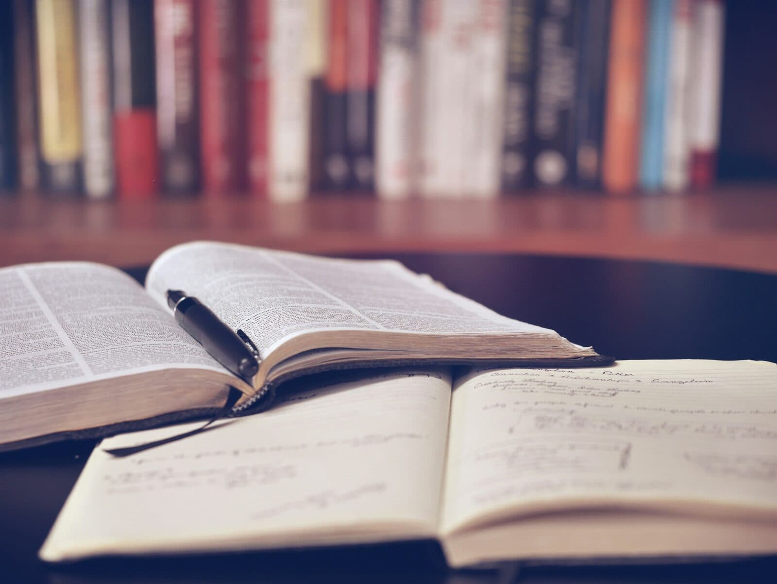 An open notebook with handwritten notes on a wooden desk, representing the organized knowledge layer in a boutique advisory practice