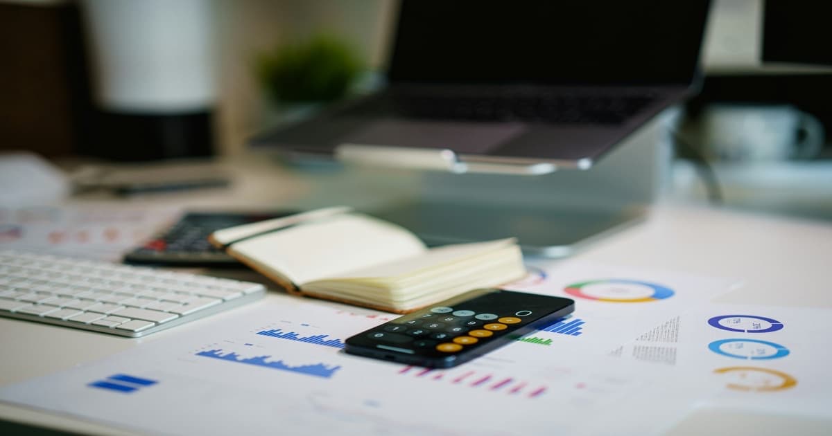 A professional advisor reviewing organized data and documents at a clean desk with a laptop open to charts