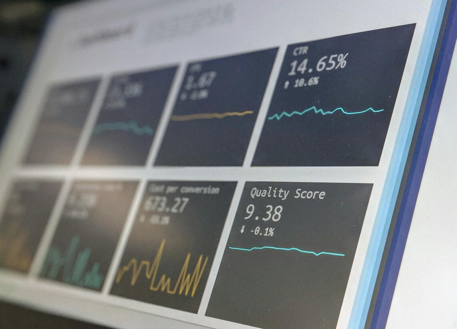 A laptop displaying data monitoring dashboards and analytics charts on screen in a dimly lit office setting