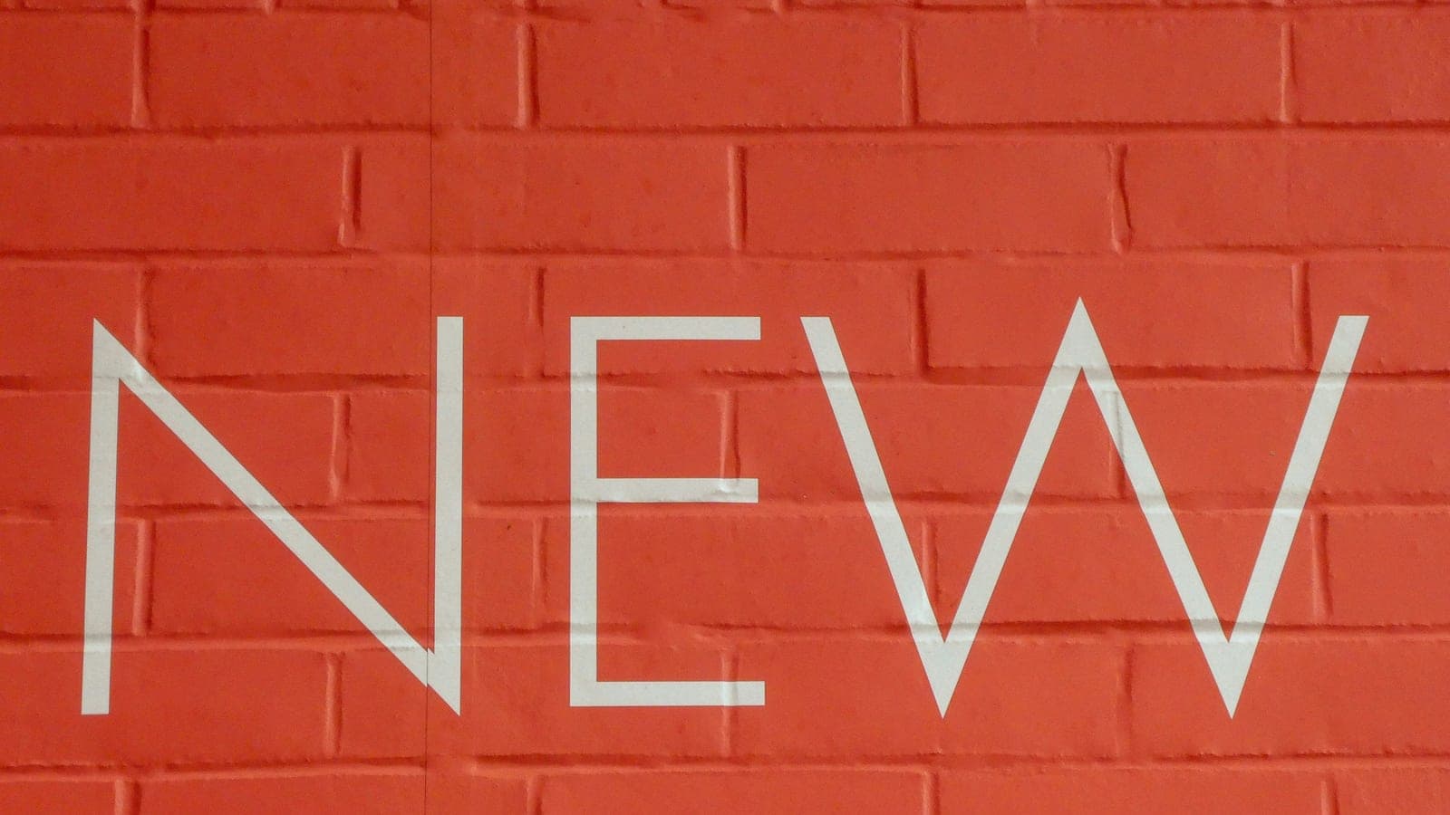 The word new on a red brick wall.