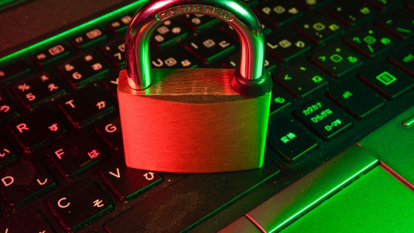 A padlock stamped "Hardened" resting on a laptop keyboard