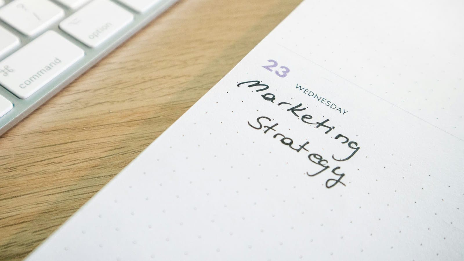 Desk with a keyboard and a planner with the words Marketing Strategy on it