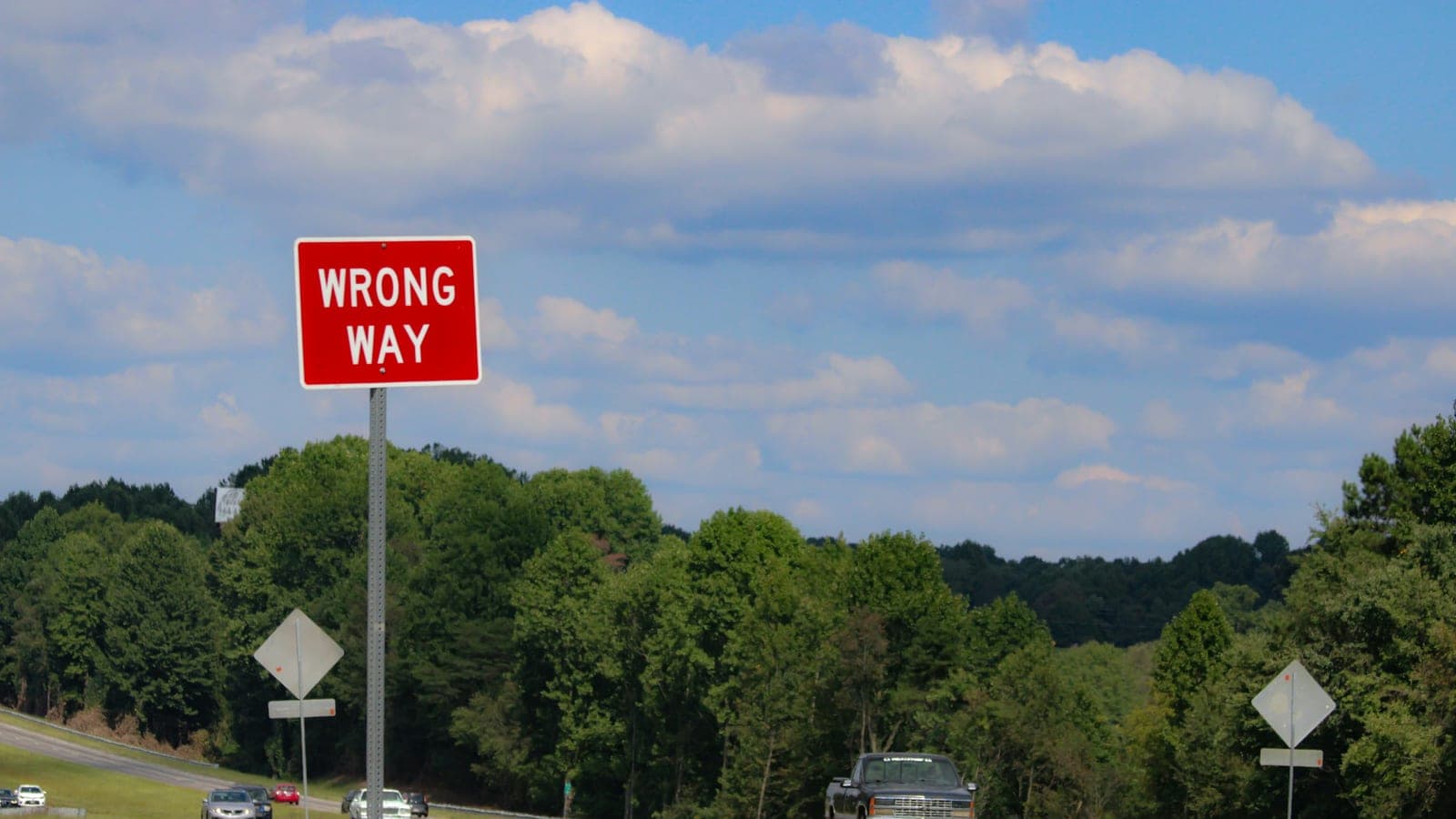 A red wrong way sign sitting on the side of a road